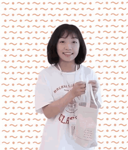 a girl in a white shirt is holding a tote bag in her hands .