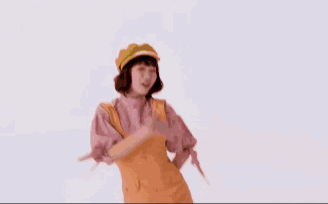 a woman in a pink shirt and orange dress is dancing against a white background .