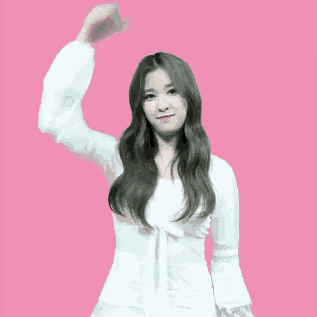 a woman in a white dress stands in front of a pink background with a cartoon drawing of a heart and the letter h