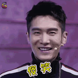 a man is smiling with a microphone in his ear and chinese writing on his face .