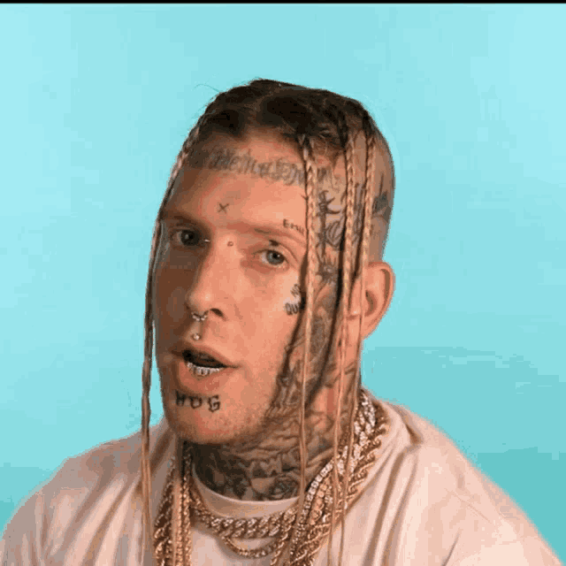 a man with dreadlocks has a tattoo on his forehead that says ' bitch '