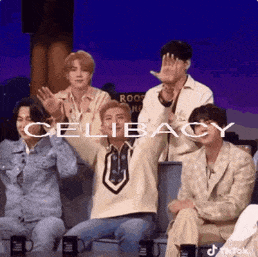 a group of people are sitting around a table with their hands in the air and the word celibacy written on the screen .