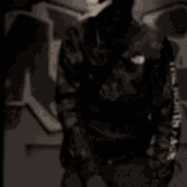 a person in a military uniform is sitting in a dark room with a door open .