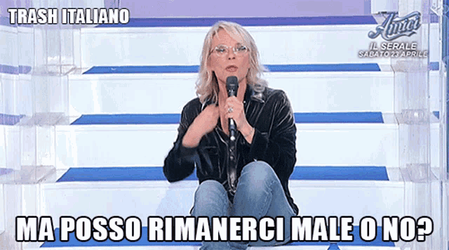 a woman sits on a set of stairs holding a microphone and says trash italiano ma posso rimanerci male o no
