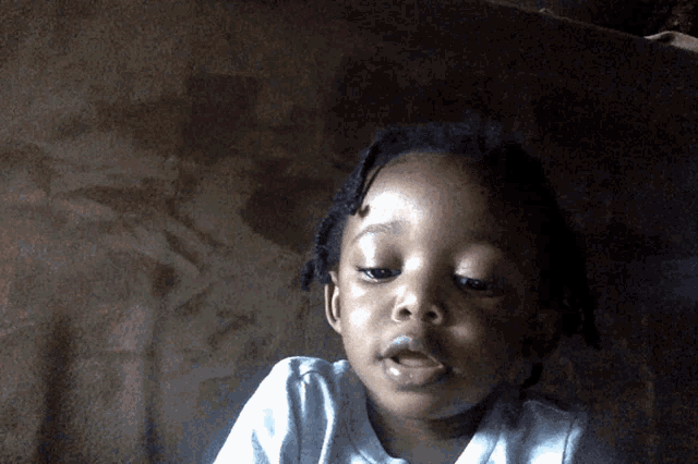 a little girl with dreadlocks is looking at the camera with her mouth open