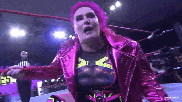 a woman with pink hair is standing in a wrestling ring