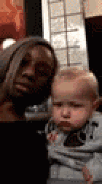 a woman is holding a baby in her arms .