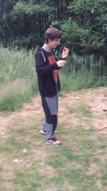 a man wearing a shirt that says ' uc ' on it stands in a field