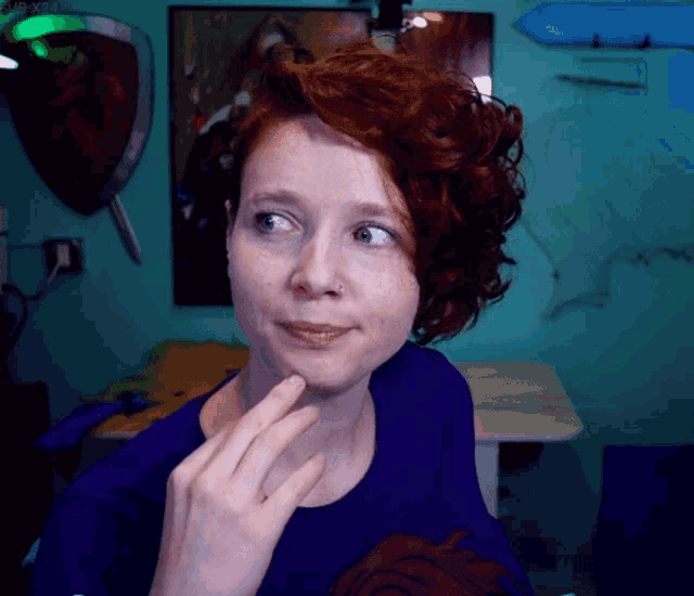 a woman with red hair is wearing a purple shirt and looking at the camera