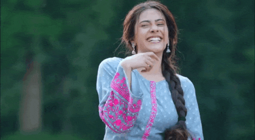 a woman in a blue and pink dress is laughing and holding her hair .