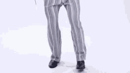 a man wearing striped pants and black shoes is dancing .