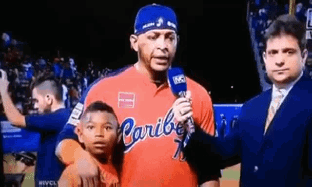 a man in a red caribbean jersey is holding a young boy