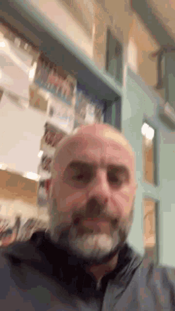 a bald man with a beard is smiling in front of a blue door