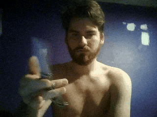 a shirtless man with a beard is holding something in his hand