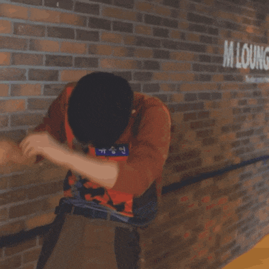 a man wearing a safety vest is crawling on the floor in front of a brick wall