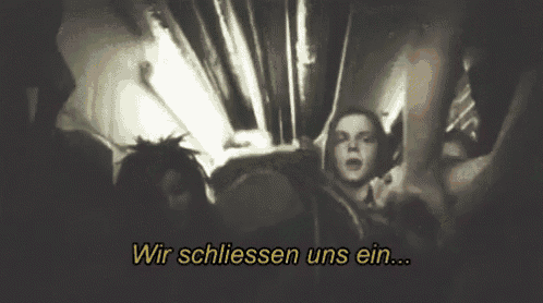 a group of people standing in a dark room with the words wir schliessen uns ein in yellow letters