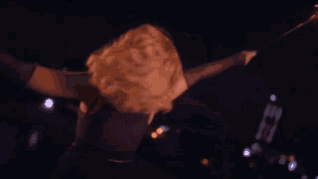 a woman in a purple top is holding a sparkler in her hand .