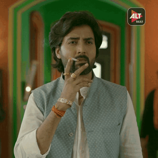 a man smoking a cigarette in front of an alt balaji sign