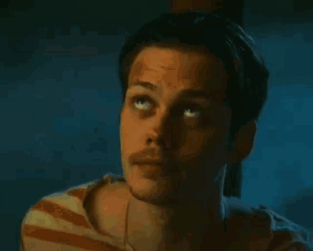 a close up of a man 's face with a striped shirt and a beard .