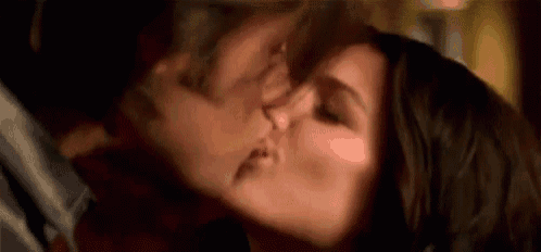 a woman is kissing a man on the cheek in a close up of their faces .