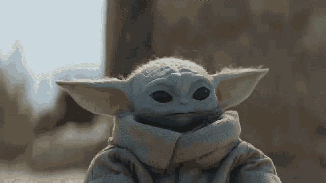a close up of a baby yoda toy with a scarf around its neck .