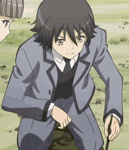 a boy in a suit and tie is kneeling down in the grass