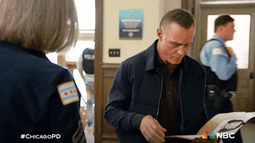 a man in a blue jacket is looking at a piece of paper with #chicagopd written on the bottom