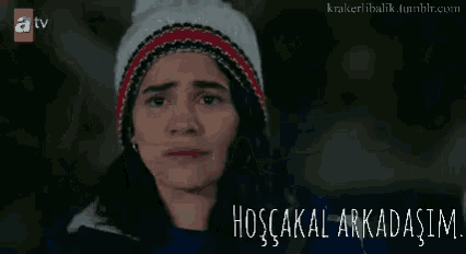 a woman wearing a hat and a blue jacket says hoşçakal arkadasim .