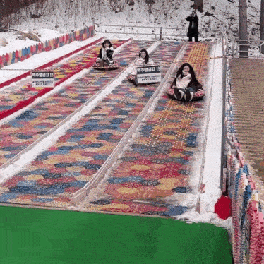 a group of people are riding down a snow slide with a sign that says ' a warning ' on it