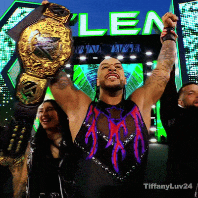 a man is holding up a wrestling championship belt in front of a sign that says len