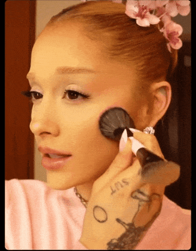 a woman with a tattoo on her finger that says slut is applying makeup