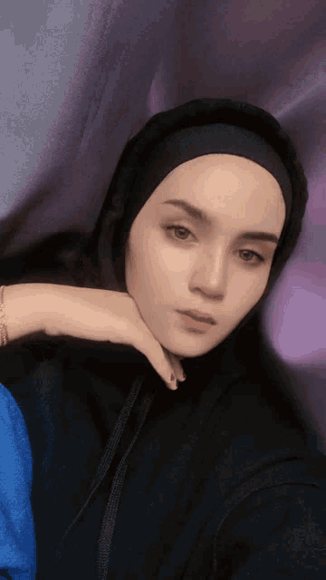 a woman wearing a headband and a black hoodie looks at the camera