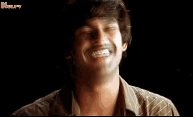 a man with a mustache is laughing with his eyes closed in front of a black background .