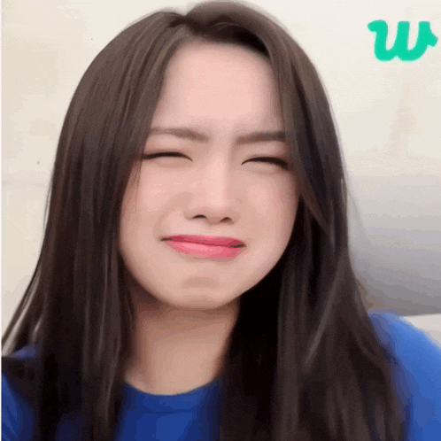 a woman in a blue shirt is making a face with her eyes closed