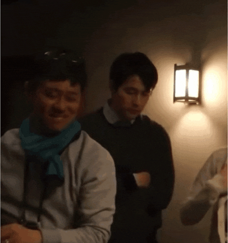 a man with a scarf around his neck is standing next to another man