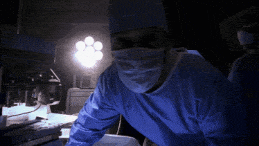 a surgeon wearing a mask and gown is standing in a dark room