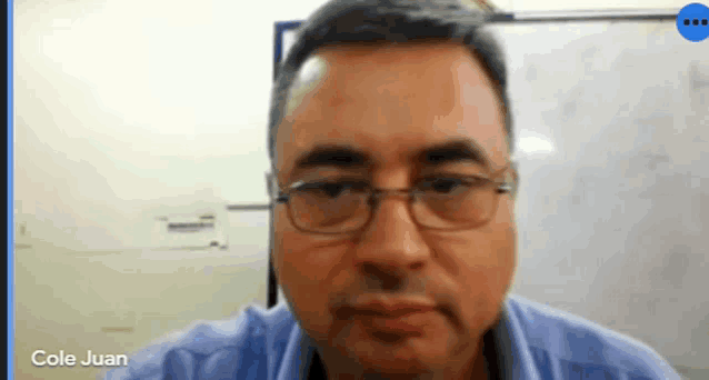 a man wearing glasses is on a video call with cole juan .