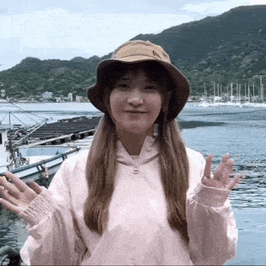 a woman wearing a hat and a pink jacket is waving