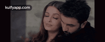 a man and a woman are hugging each other and smiling with their eyes closed .