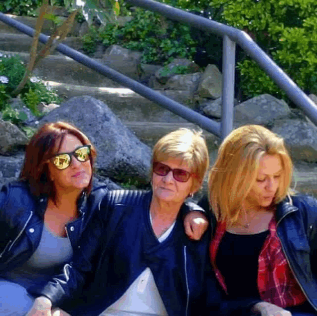 three women wearing sunglasses are sitting next to each other on a set of stairs