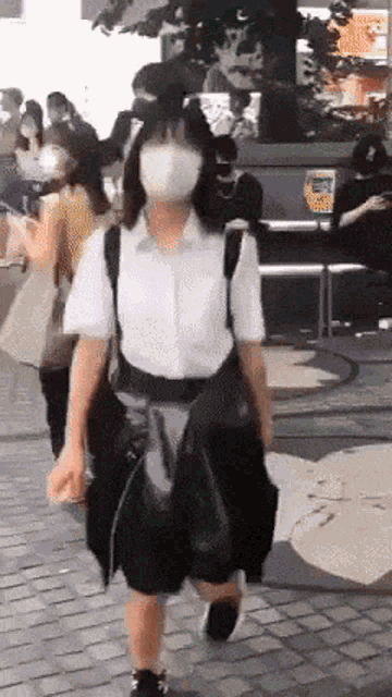 a woman wearing a mask walking down a street