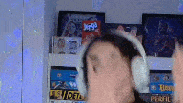 a woman wearing headphones is standing in front of a shelf full of board games including jenga .