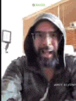 a man with a beard and glasses is wearing a hoodie and goggles .