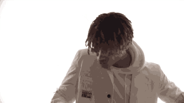 a young man wearing a white jacket and a white hoodie is dancing in front of a white background .