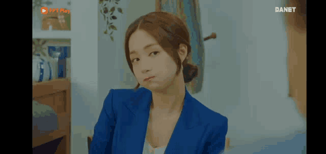 a woman in a blue suit is making a funny face while sitting at a table .