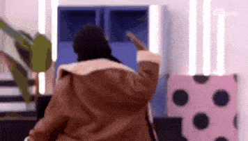 a woman in a brown coat is dancing in a room with polka dots on the walls .