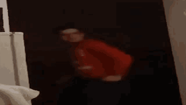 a blurry picture of a man in a red jacket standing in a dark room