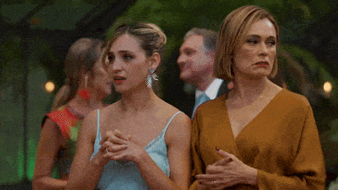 two women standing next to each other with their hands folded in front of a group of people .