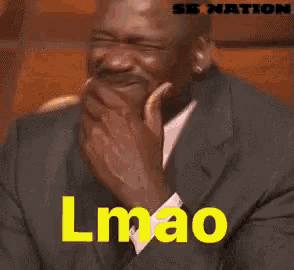 a man in a suit and tie is laughing with the word lmao in yellow