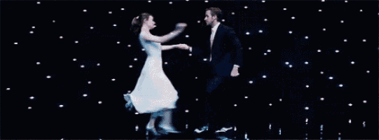 a man and a woman are dancing together on a stage . the woman is wearing a white dress .